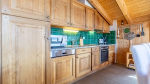A kitchen with wooden cabinets, a microwave, and a stove. - Balcons du Soleil Y2 221 - QUIET apartment 8 pers (Veysonnaz)