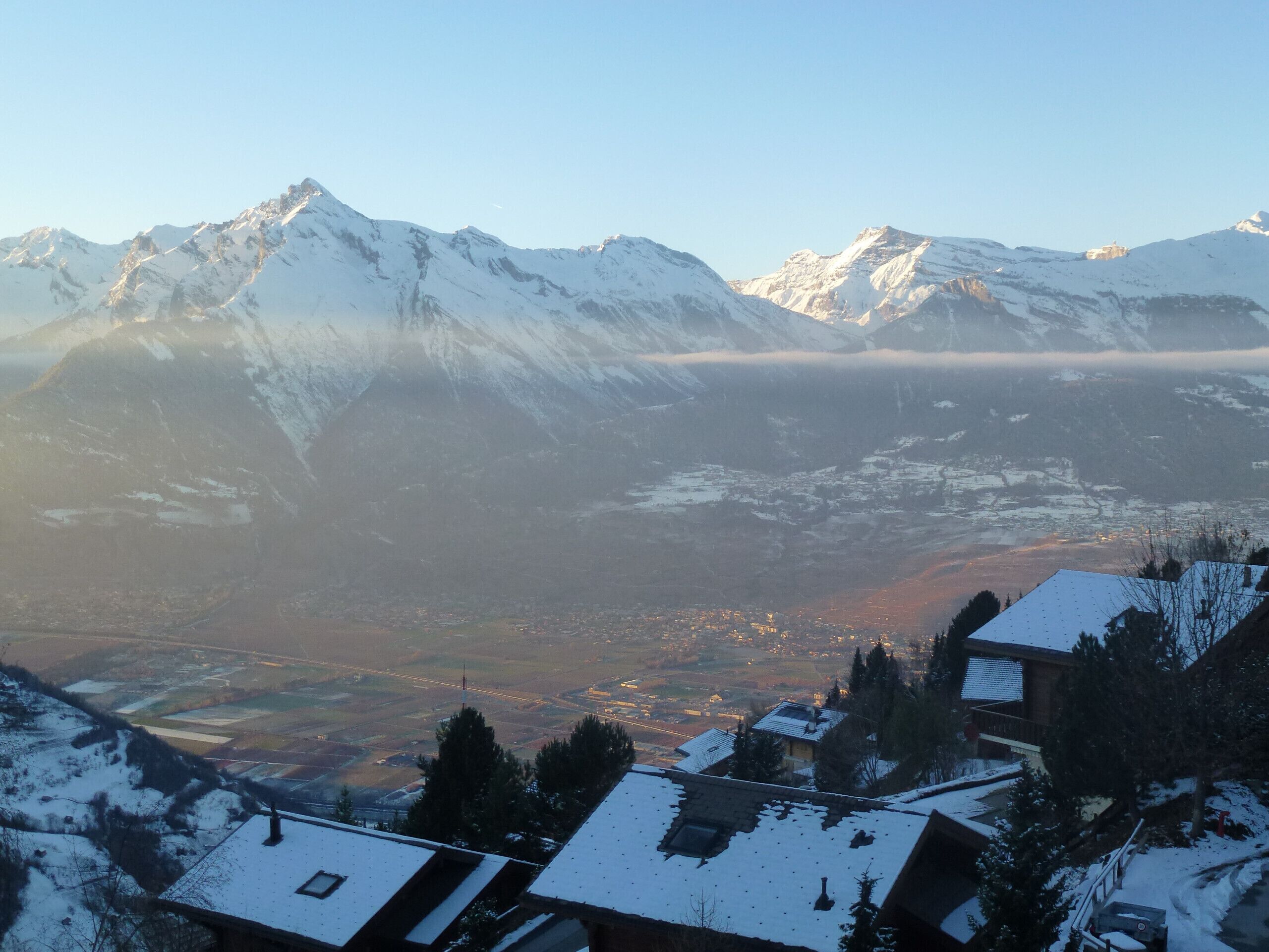 A mountain landscape with snow-covered peaks and a valley below.