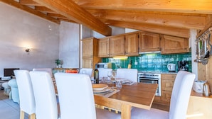 A wooden dining table with white chairs, a kitchen with wooden cabinets, and a green tiled backsplash. - Balcons du Soleil Y2 221 - QUIET apartment 8 pers (Veysonnaz)