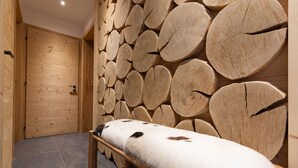 Um quarto com painel de parede de madeira, um banco com cobertura de pele e uma porta.