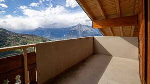A balcony with a view of mountains and a wooden ceiling.