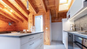 A modern kitchen with wooden beams, a large island with a sink, and built-in appliances.