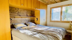 A bedroom with a wooden ceiling, a bed with white bedding, and a window with a view of greenery. - Fontanettaz V 007 - MOUNTAIN apartment 8 pers (Veysonnaz)