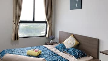 A bedroom with a bed, a nightstand, a window with curtains, a wall-mounted picture, and a bedside table.