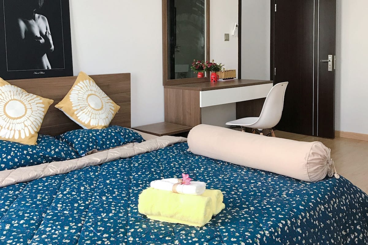 Een slaapkamer met een bed, een bureau, een stoel, een kledingkast, een spiegel en een airconditioner.
