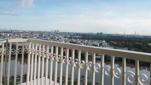 A balcony with a view of a cityscape, including buildings and a river.