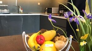 A kitchen with white cabinets, a black refrigerator, and a fruit bowl on the counter.