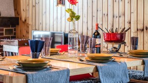 A dining table set with plates, glasses, and a vase with a red rose.