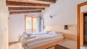 A wooden bed with a headboard, a small bedside table, and a window with curtains.