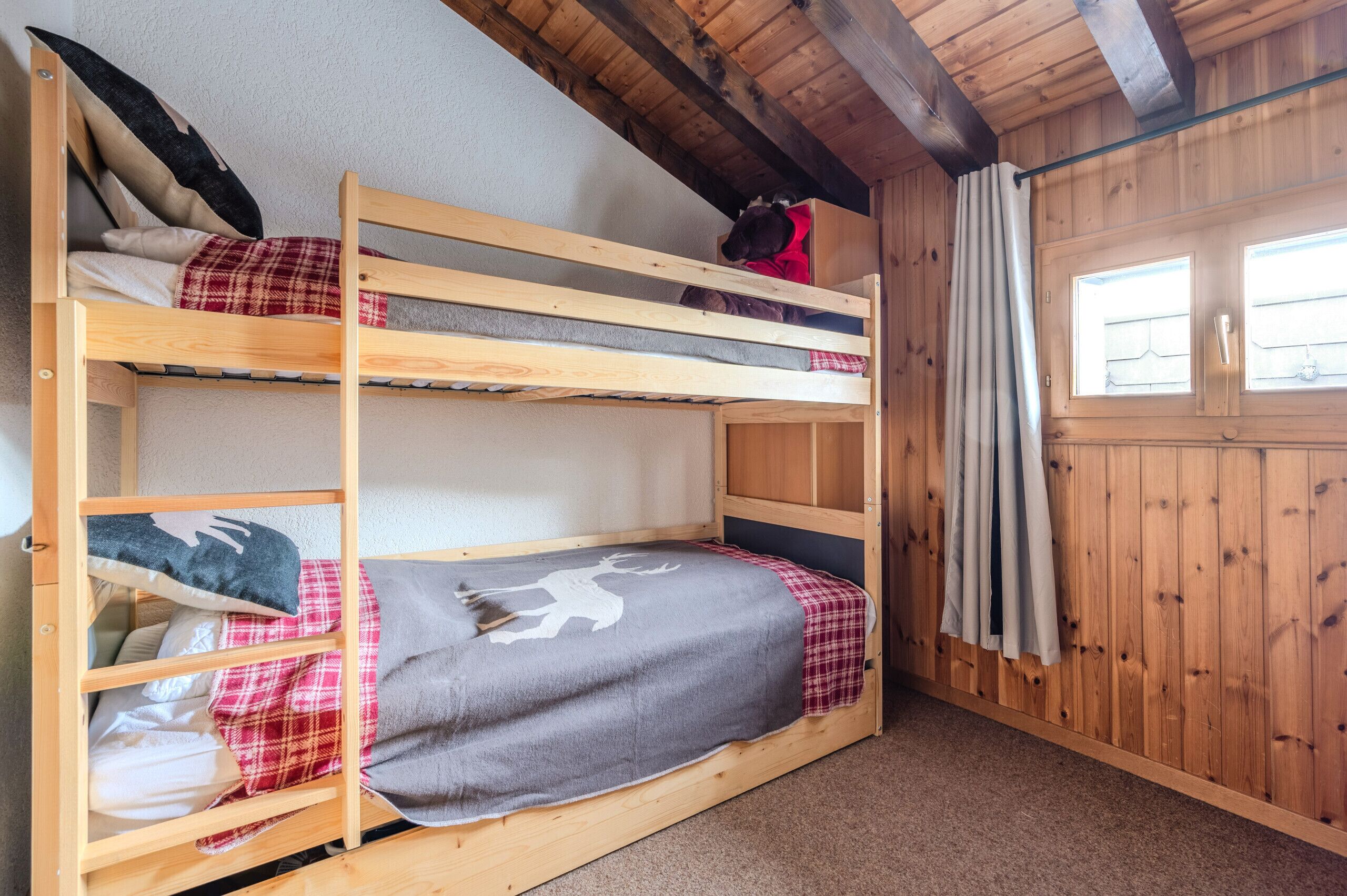 A bunk bed room with wooden walls and a window.
