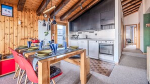 A wooden interior with a dining area, kitchen, and a view of the outside.