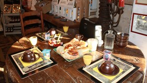 A wooden table with breakfast items, including bread, butter, and a teapot. - Logis Les Remparts (Bayeux)