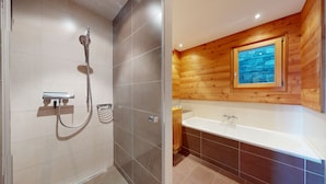 Un baño moderno con ducha, bañera y paneles de madera.