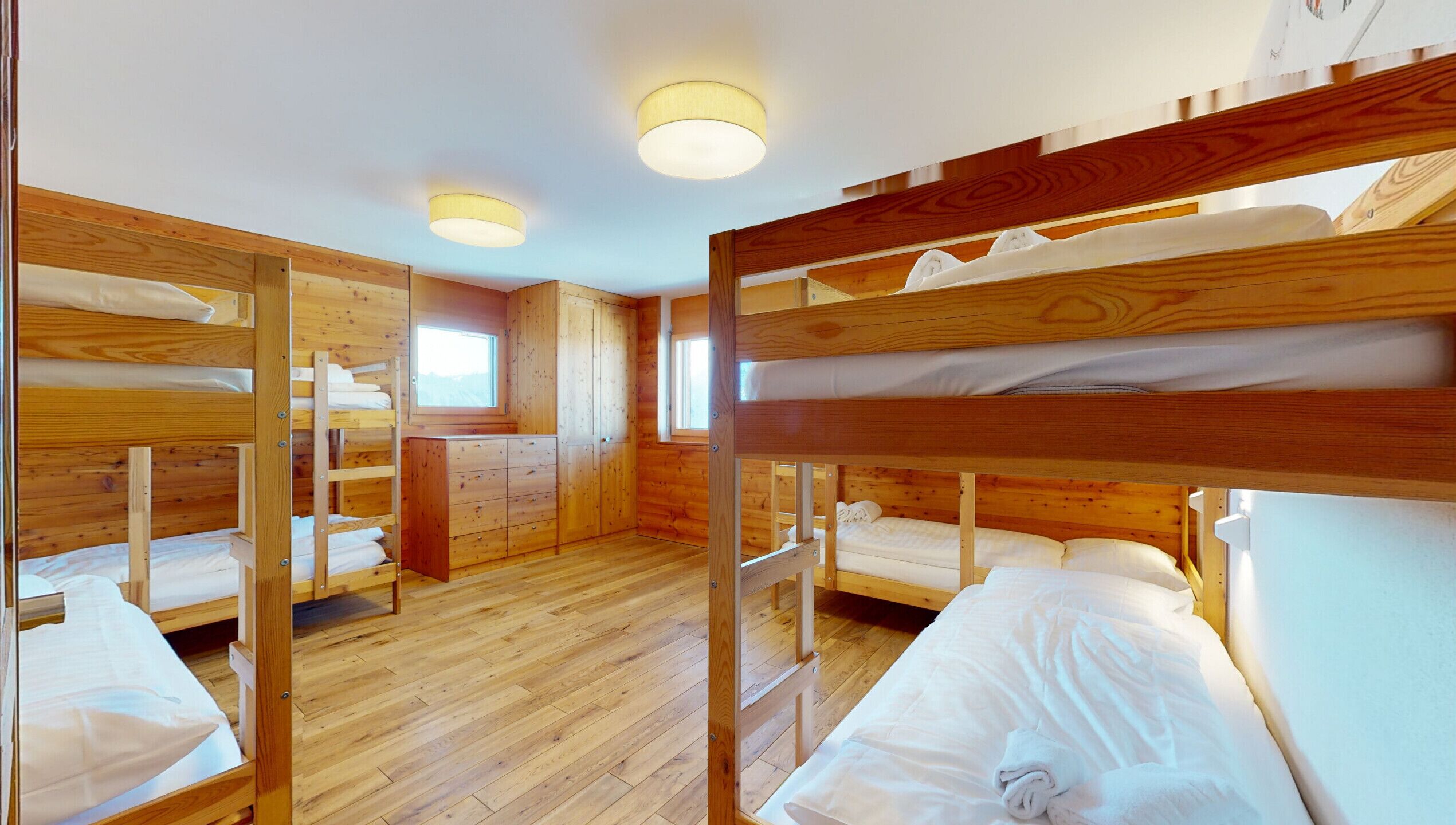 Eine Holzhütte mit Etagenbetten, Holzwänden, einem Fenster und einem kleinen Schreibtisch.