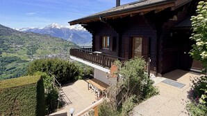 Un chalet en bois doté d’un balcon donnant sur un paysage montagneux.