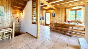 Un intérieur en bois comprenant un espace cuisine, des poutres apparentes et une grande fenêtre.