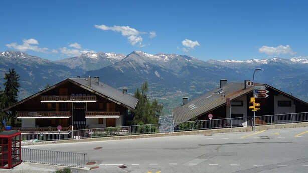 Un hôtel doté d’un balcon, d’une enseigne indiquant la présence d’un restaurant et offrant une vue sur des montagnes enneigées.
