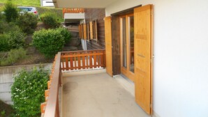 A balcony with wooden railings, a concrete floor, and a wooden door.