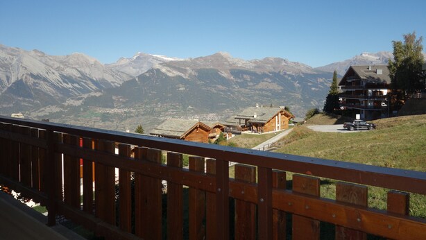 A mountain view with wooden cabins and a large building with a balcony.