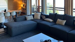Een modern interieur met een hoekbank, een eethoek en grote ramen.