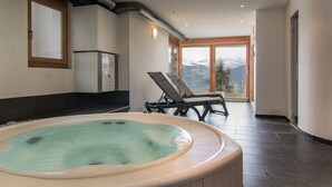 A spa area with a hot tub, lounge chairs, and a view of mountains.