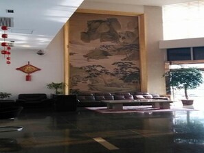 A lobby with a large wall mural, seating area, and potted plants.