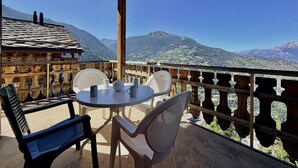 Un balcón con mesa y sillas, con vistas a un paisaje montañoso.
