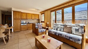 A cozy interior with a wooden sofa, a dining table, and a kitchen area with wooden cabinets.