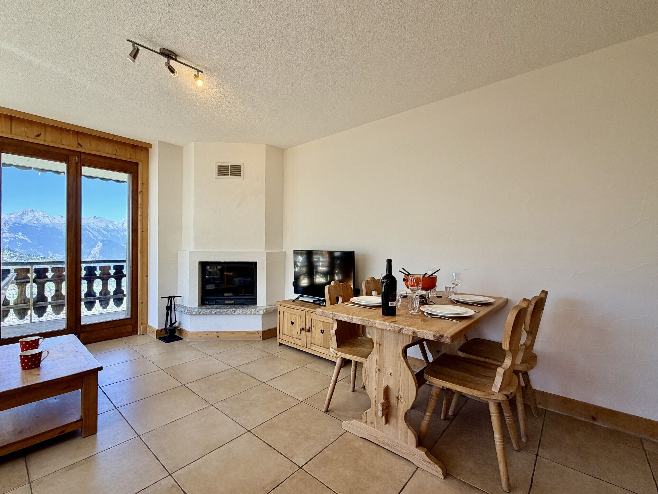 Ein Essbereich mit Tisch für zwei Personen, einem Fernseher und einem Kamin.
