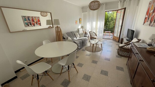 Un salon moderne comprenant un coin repas, un canapé, un téléviseur et une grande fenêtre avec des rideaux.