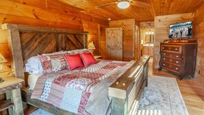 A wooden cabin bedroom with a bed, a dresser, a ceiling fan, and a television. - Mountain Lodge Near Downtown (Boone)