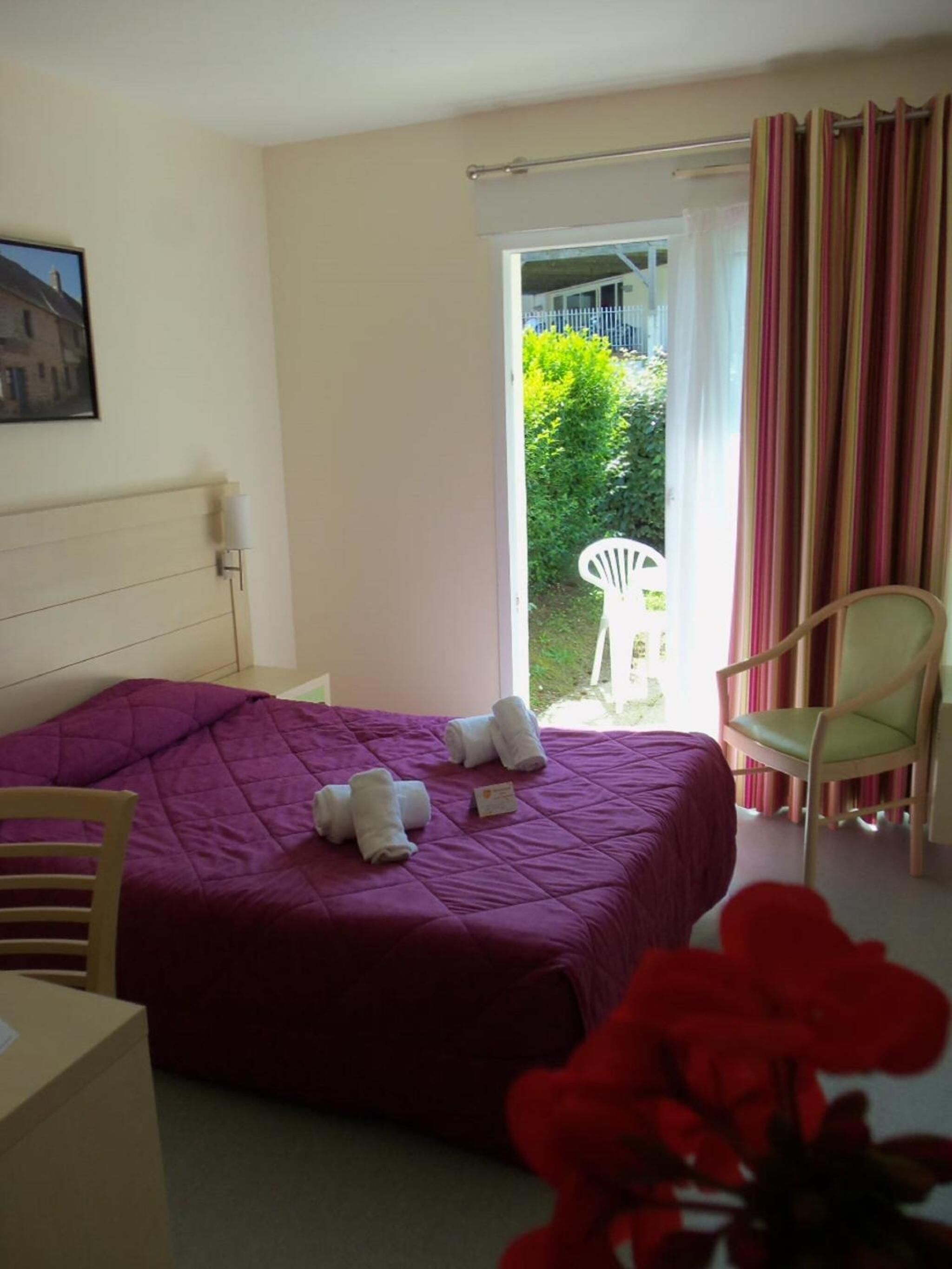 Ein Schlafzimmer mit Bett, Stuhl, Tisch und Blick ins Freie.