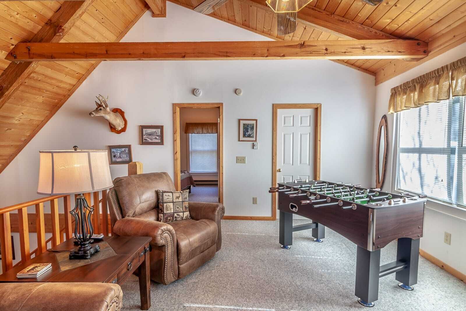 A cozy room with a leather sofa, a foosball table, and a lamp.
