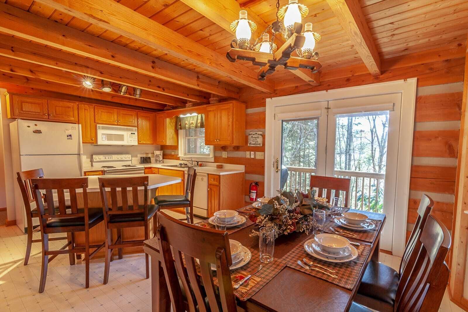 A cozy cabin-style kitchen with wooden cabinets, a central island, and a dining area set for four.