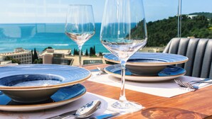 A table set with blue and white plates, two wine glasses, and cutlery, overlooking a coastal view. - Lusso Mare by Aycon (Budva)