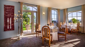 A dining area with a table set for two, large windows, and a chandelier. - Hotel Kalenborner Hoehe (Kalenborn)