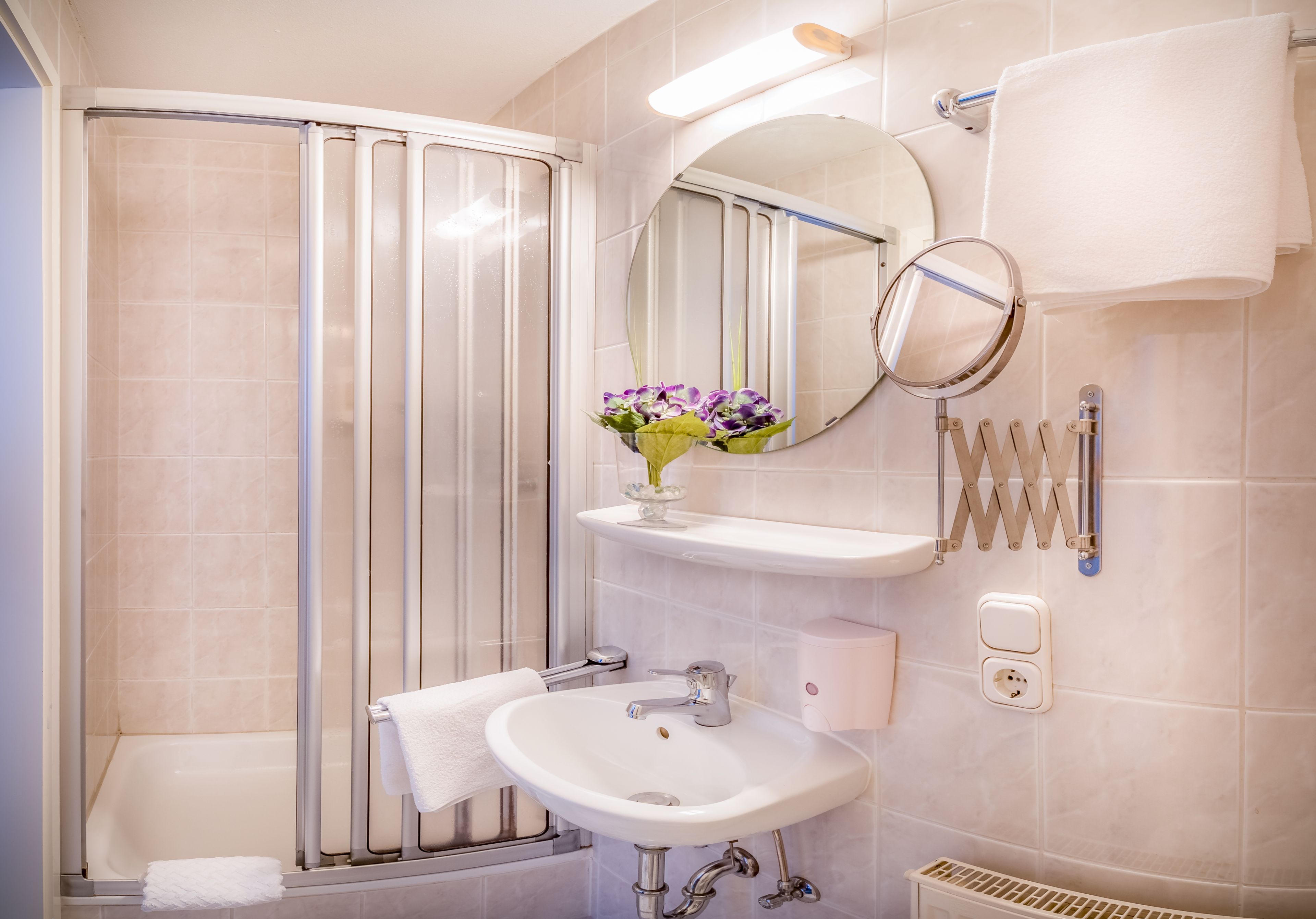 Un baño moderno con ducha, lavabo y espejo.