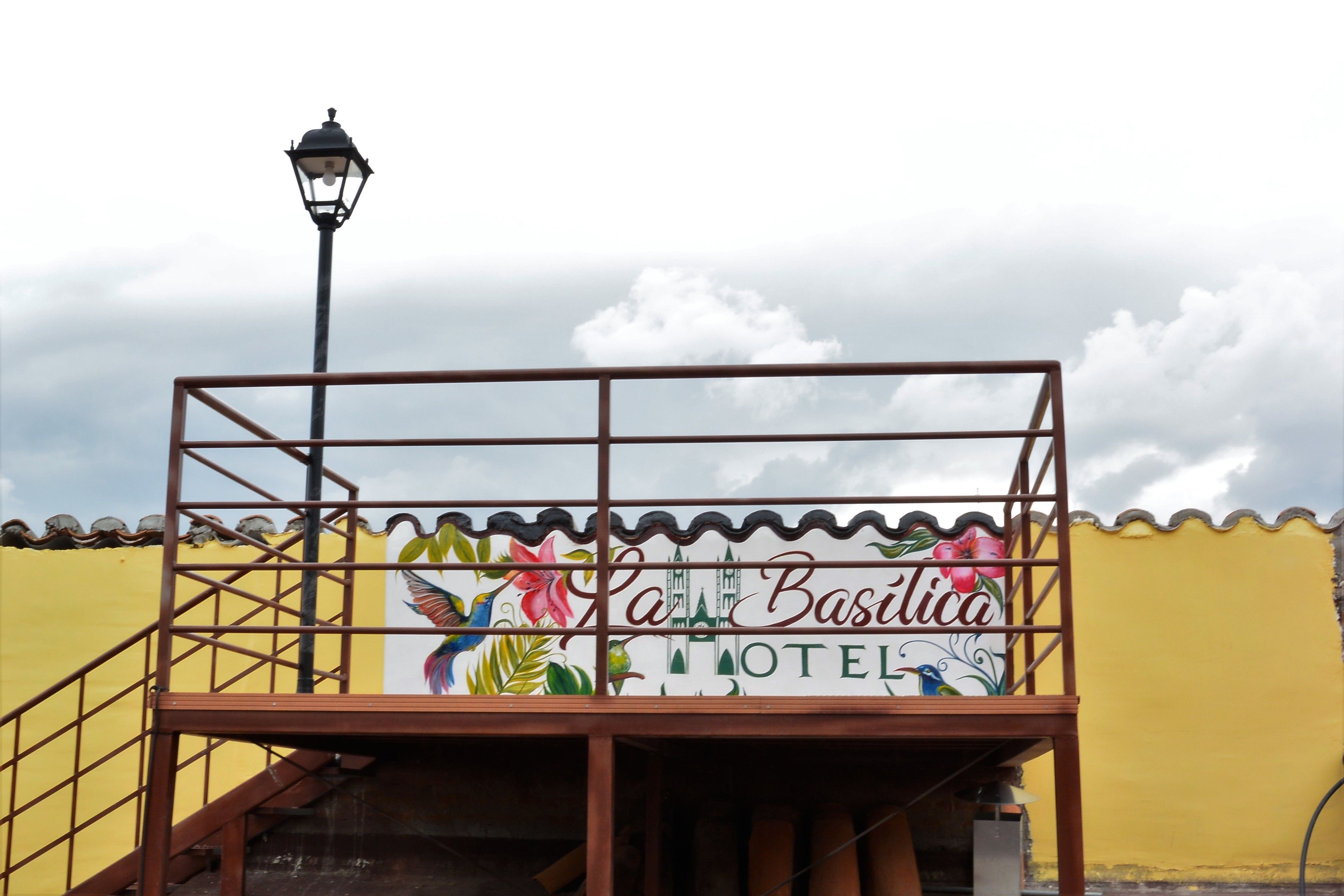 Entrada de hotel con una escalera, barandilla metálica y farola.