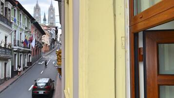 A street view from a balcony with a view of a city street, buildings, and a car.
