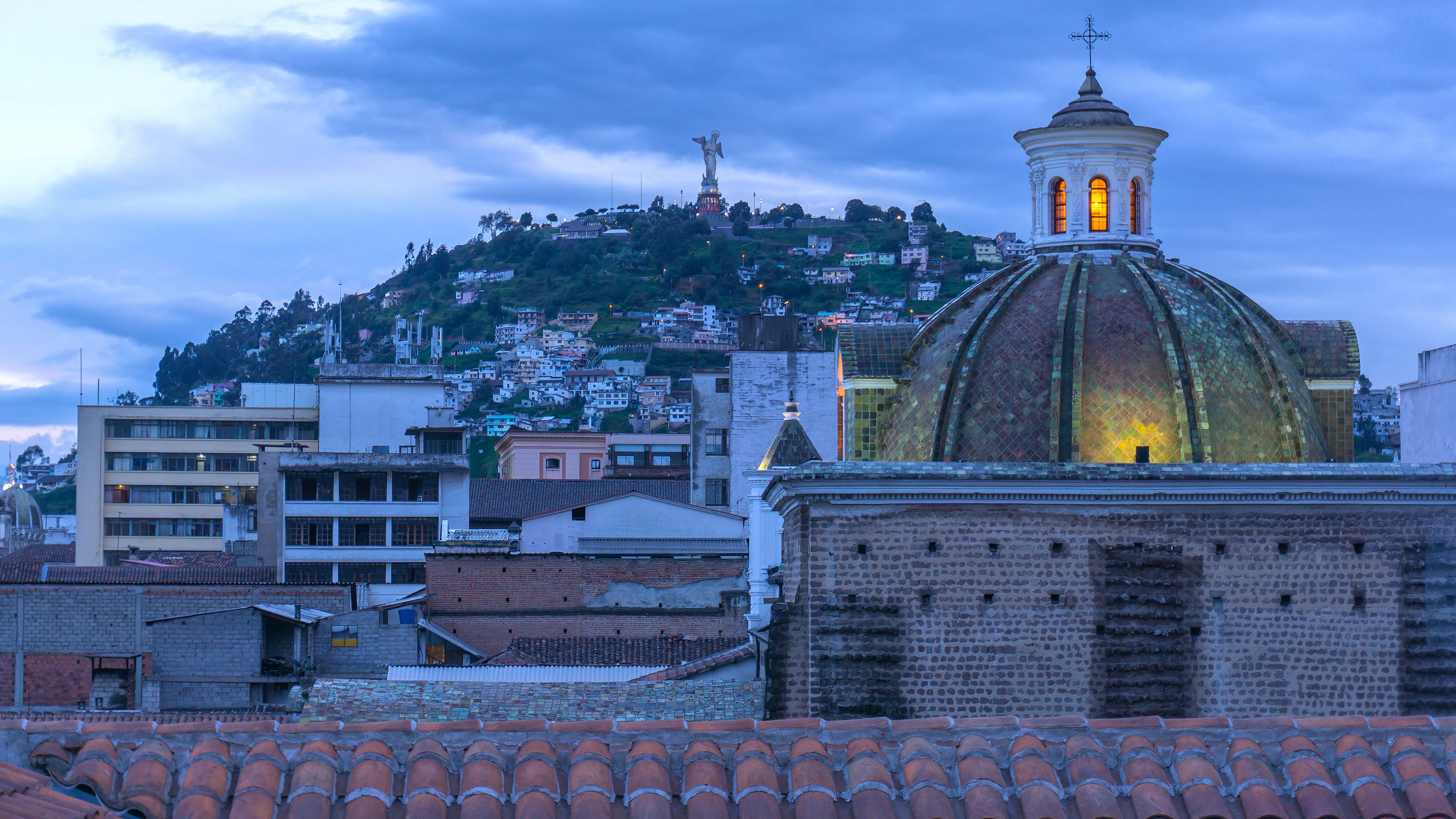 A cityscape with a prominent dome and a cross atop a hill.