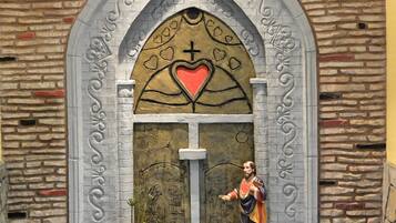 A chapel with a stone facade, a cross, and a statue of a robed figure.