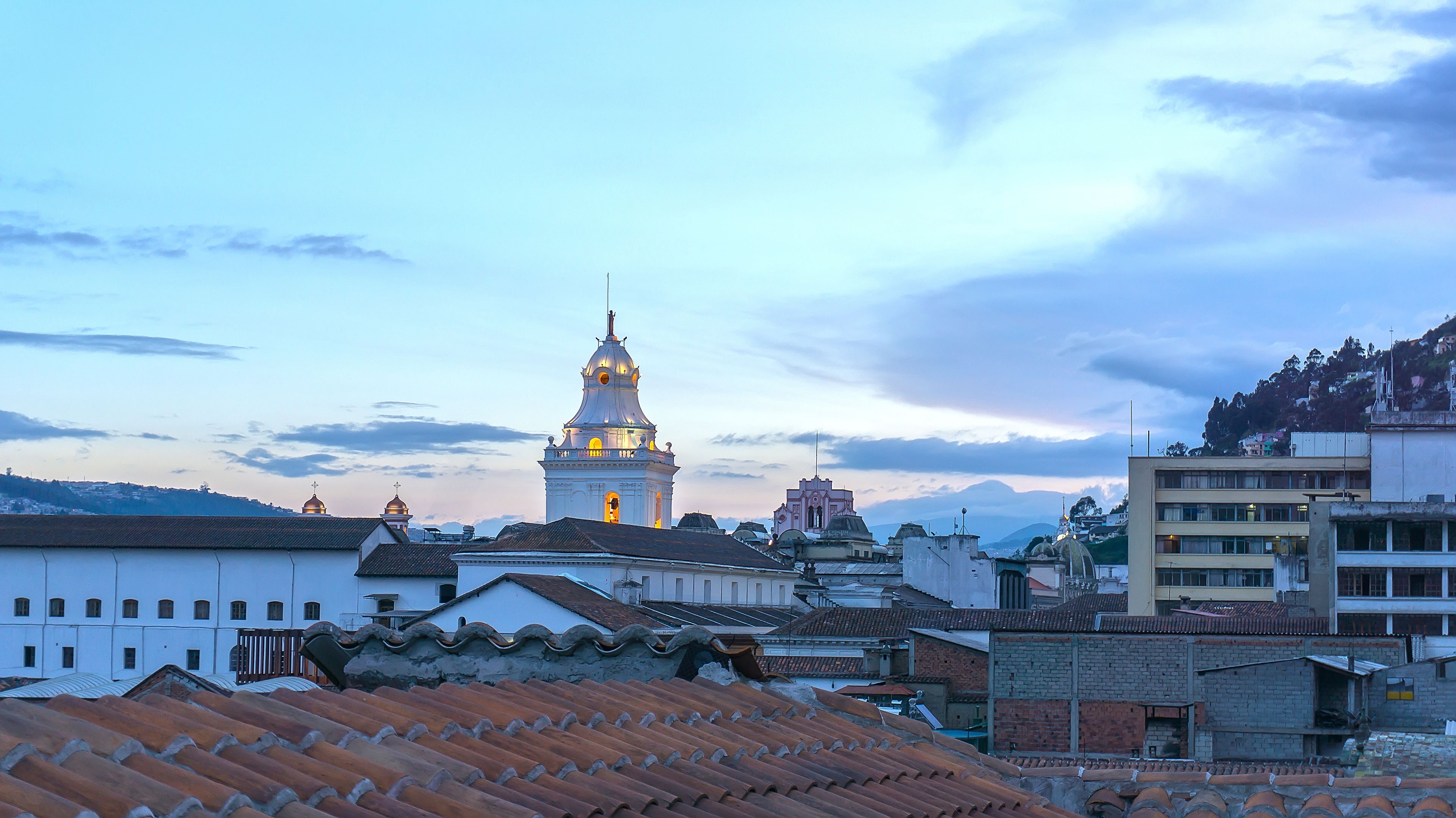 A cityscape with a prominent church tower, terracotta rooftops, and a mix of residential and commercial buildings.