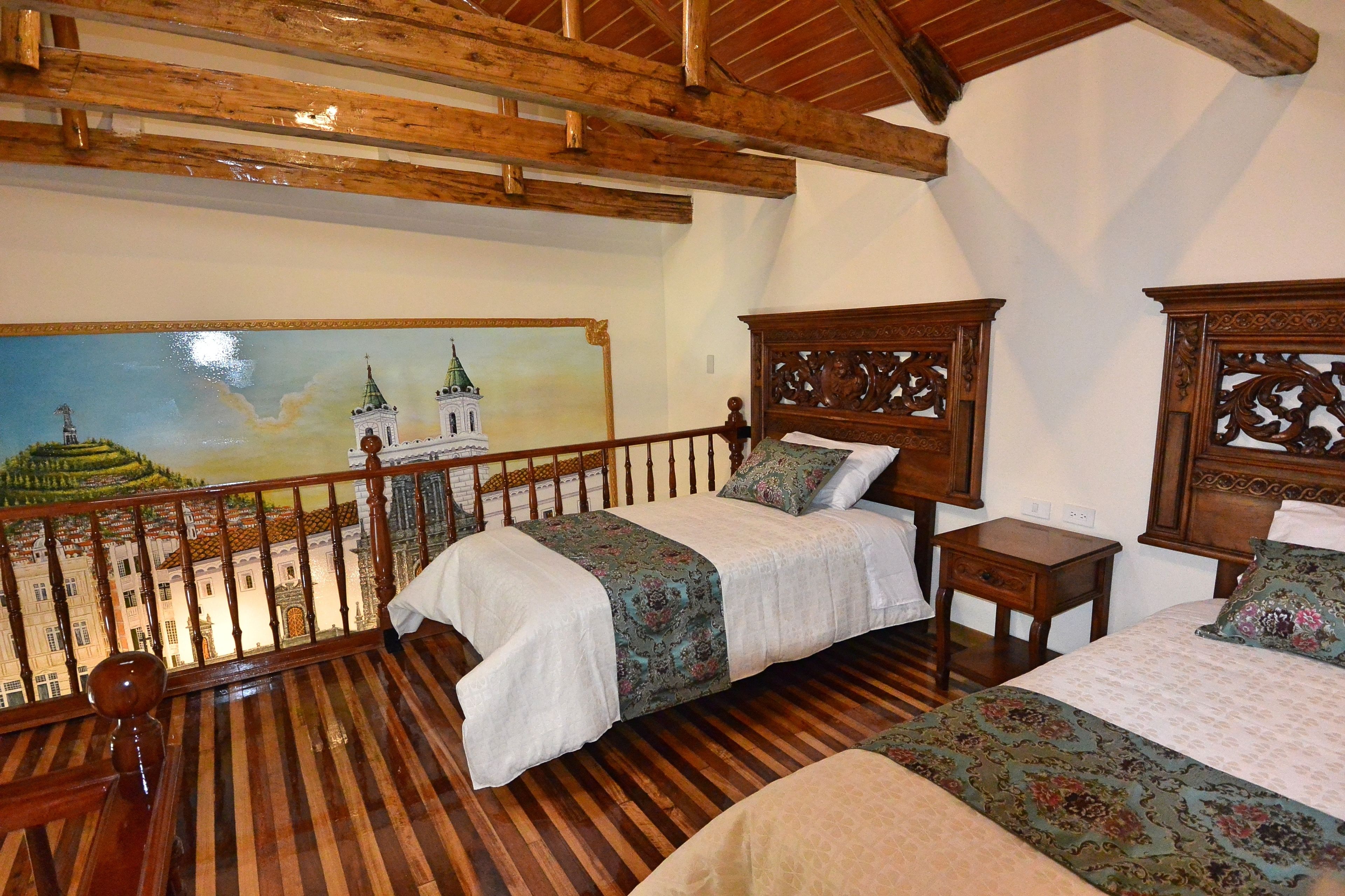 Una habitación con dos camas de madera, una mesita de noche de madera y un balcón con un mural de un edificio.