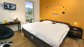 A bedroom with a bed, bedside tables, a desk with a chair, a TV, and a window with a view.