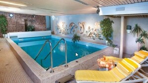 An indoor swimming pool with a tiled floor, a mural on the wall, and yellow lounge chairs. - Hotel Pohl zum Rosenberg (Kinheim)