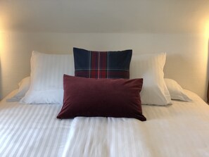 A bed with white bedding and three pillows: a white one, a plaid one, and a solid maroon one. - Hôtel Génépi (Beuil)
