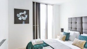 Una camera da letto moderna con un letto grande, una coperta verde e un'opera d'arte a parete raffigurante un fiore.