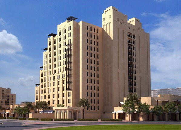 Un hôtel de grande hauteur, doté de nombreux étages, de balcons et d’une cour intérieure agrémentée de palmiers.