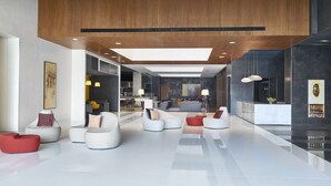 Een ruime lobby met moderne zitplaatsen, een receptiebalie en een groot kunstwerk aan de muur.