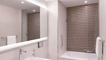 Une salle de bain moderne avec un grand miroir, un lavabo blanc, une baignoire et un espace douche.